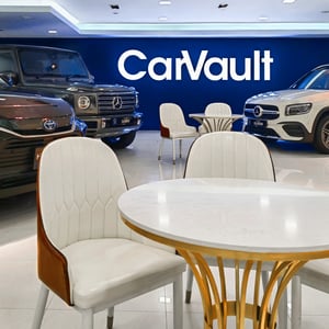 Chairs and Table in Front of Cars in a Showroom